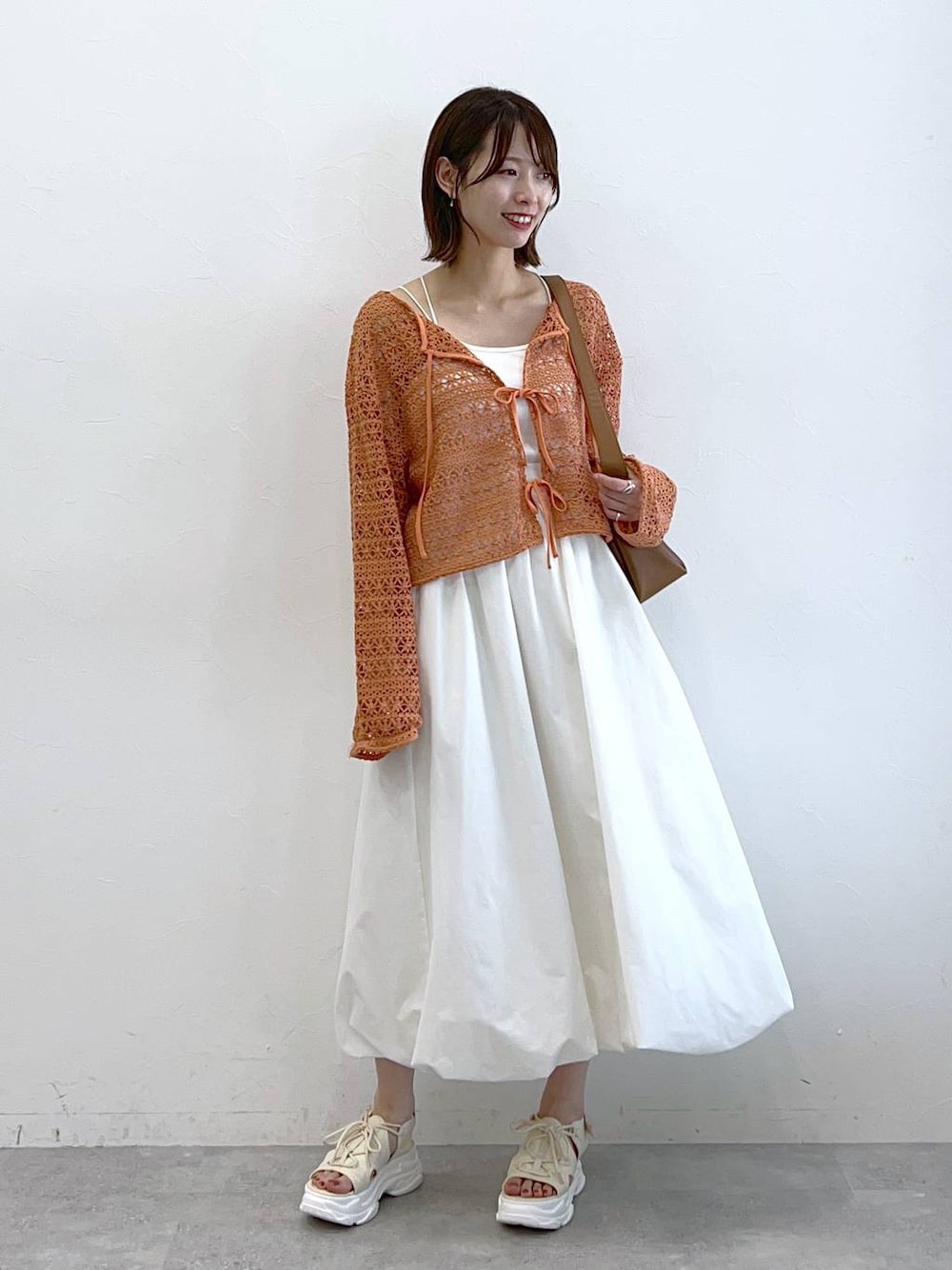 ホワイト系のサンダル、オレンジ系のカーディガン/ボレロ、ホワイト系のキャミソールを着用したレディースの春コーディネートの1枚目の写真