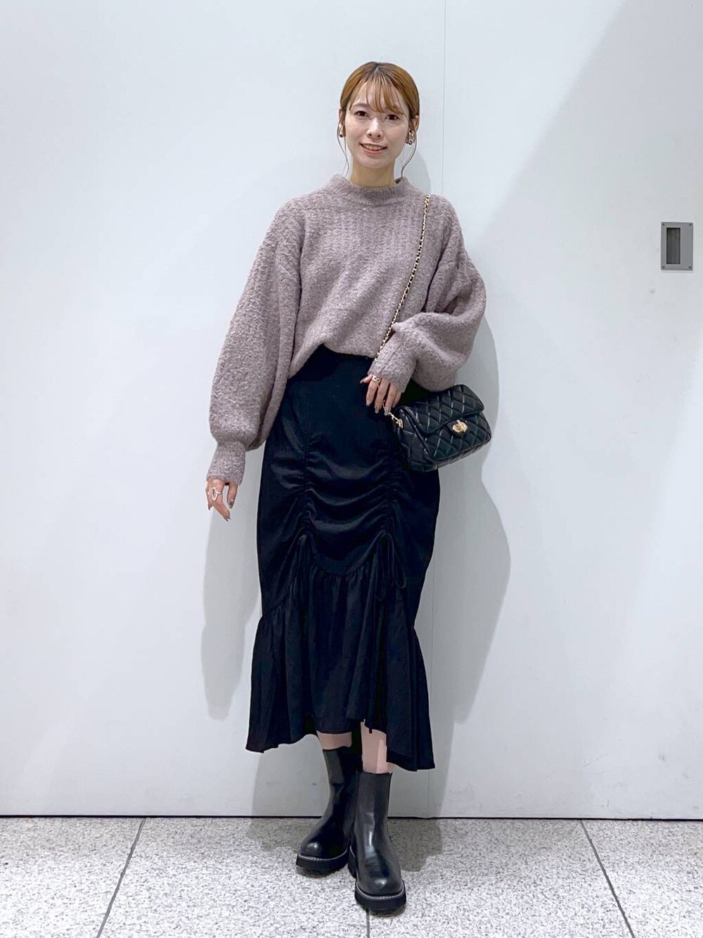 ブラック系のショルダーバッグ、ブラック系のブーツ、ブラウン系のニット/セーターを着用したレディースの秋コーディネートの1枚目の写真