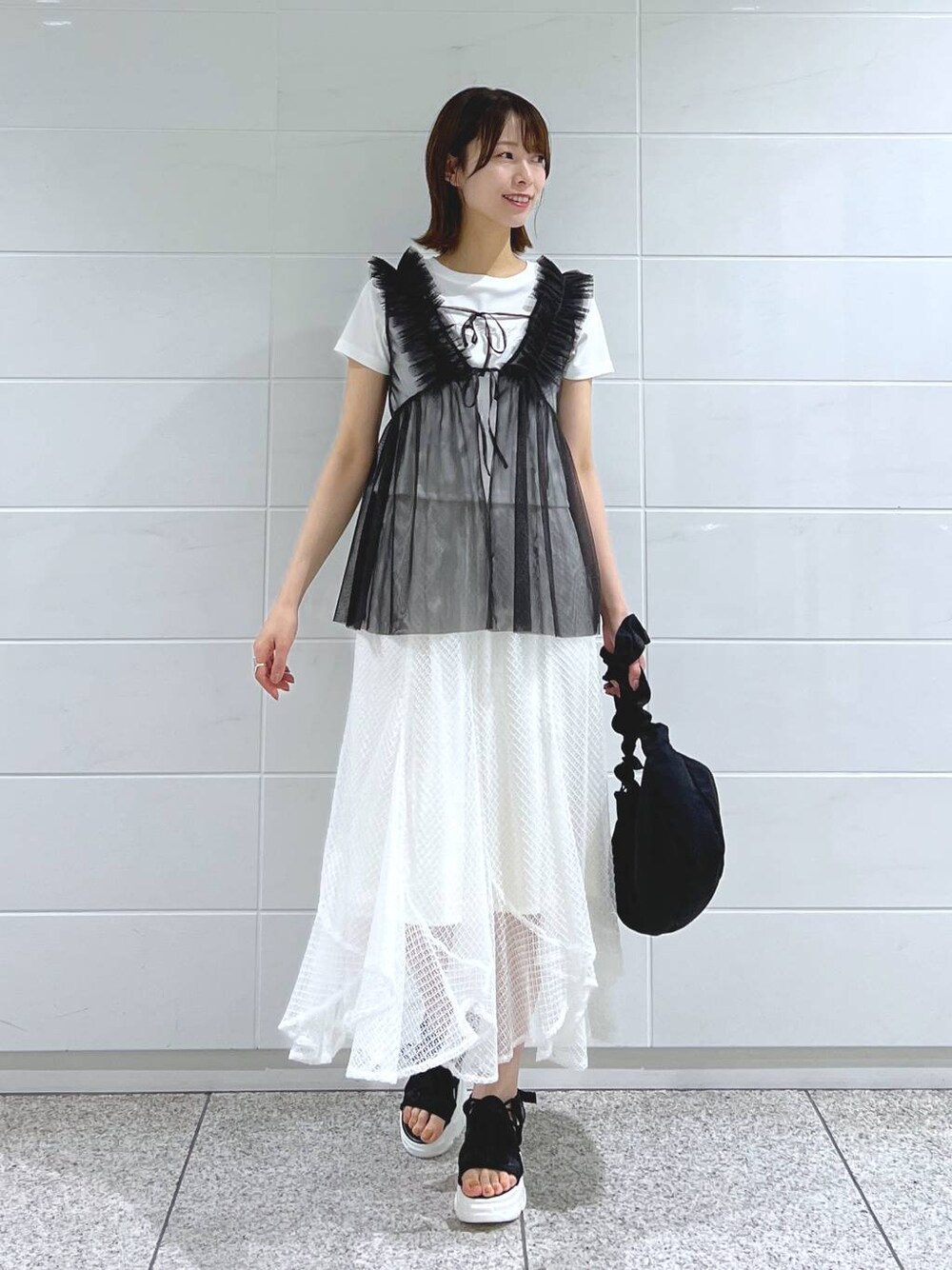 ブラック系のサンダル、ホワイト系のTシャツ/カットソー、ブラック系のショルダーバッグを着用したレディースの夏コーディネートの1枚目の写真