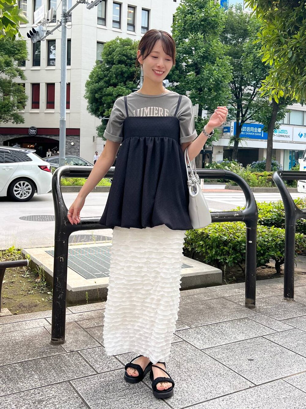ブラック系のサンダル、シルバー系のハンドバッグ、ホワイト系のスカートを着用したレディースの夏コーディネートの1枚目の写真