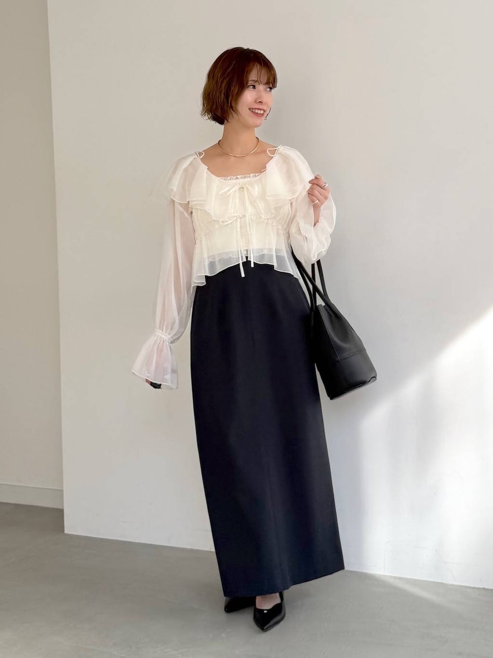 ブラック系のパンプス、ホワイト系のシャツ/ブラウス、ブルー系のスカートを着用したレディースの春コーディネートの1枚目の写真