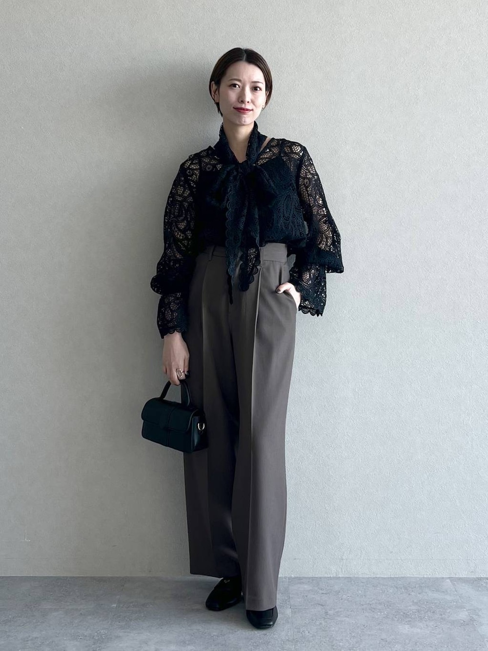 ブラック系のシャツ/ブラウス、ブラウン系のスラックス、ブラック系のローファーを着用したレディースの秋コーディネートの1枚目の写真