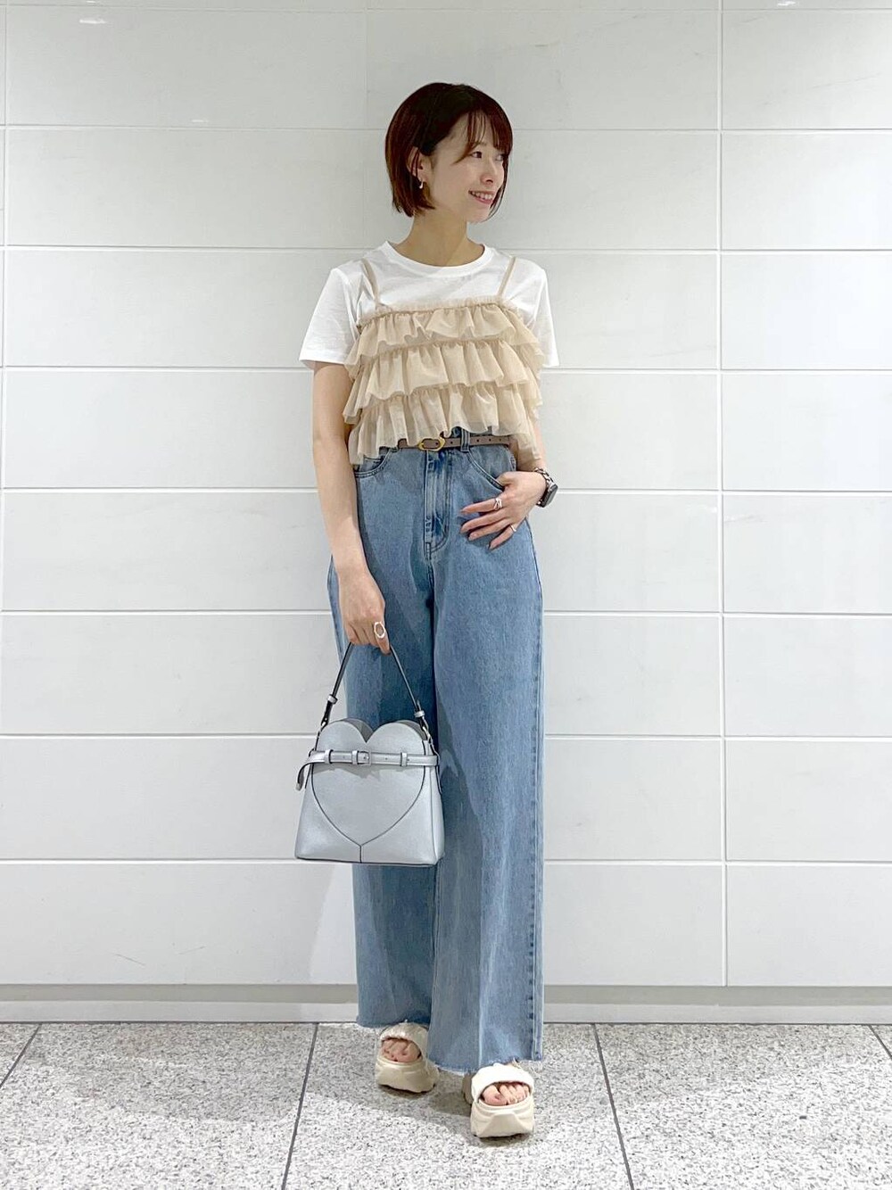 ブルー系のデニムパンツ、ホワイト系のサンダル、シルバー系のショルダーバッグを着用したレディースの夏コーディネートの1枚目の写真