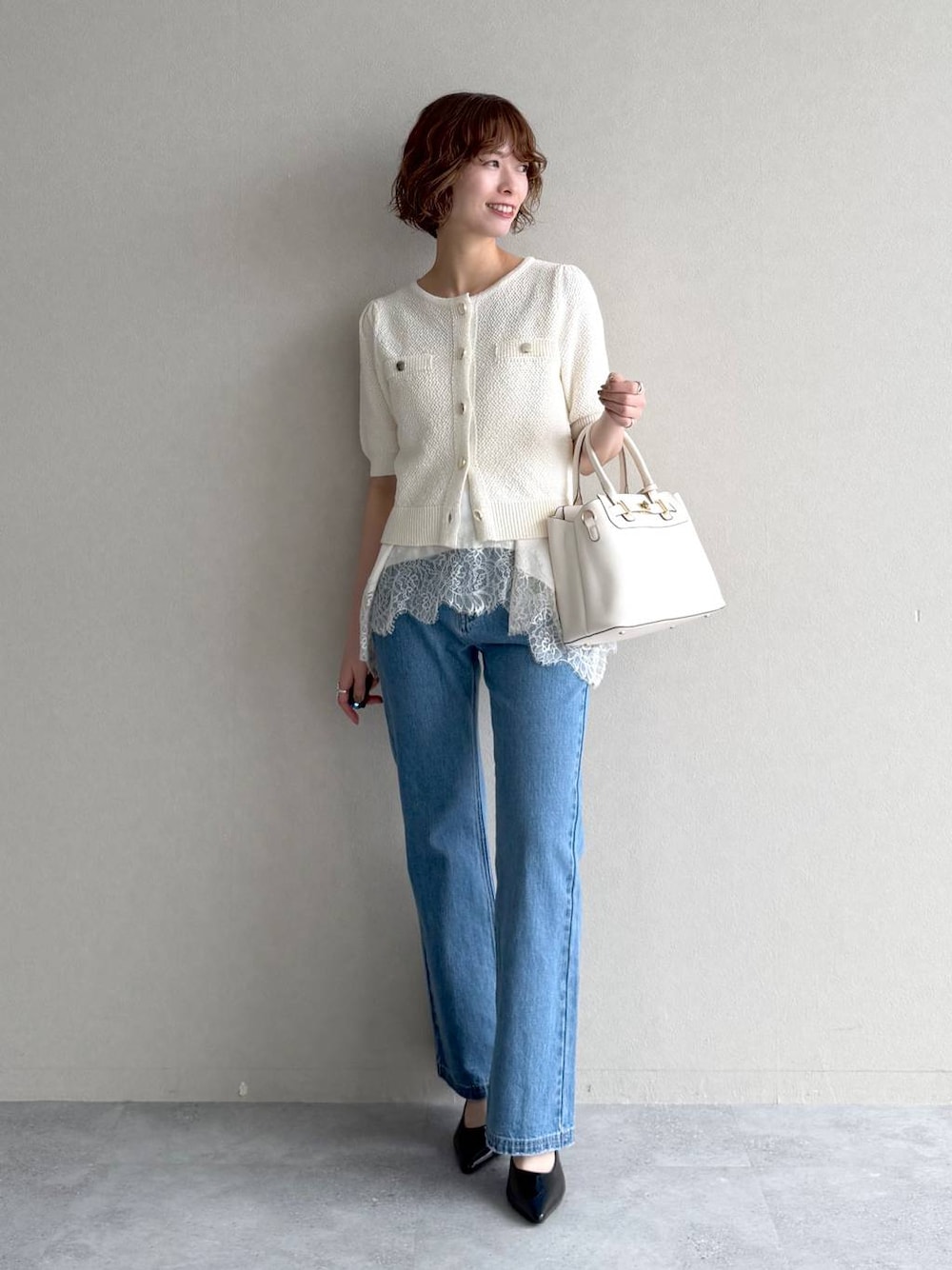 ホワイト系のカーディガン/ボレロ、ブルー系のデニムパンツ、ブラック系のサンダルを着用したレディースの春コーディネートの1枚目の写真