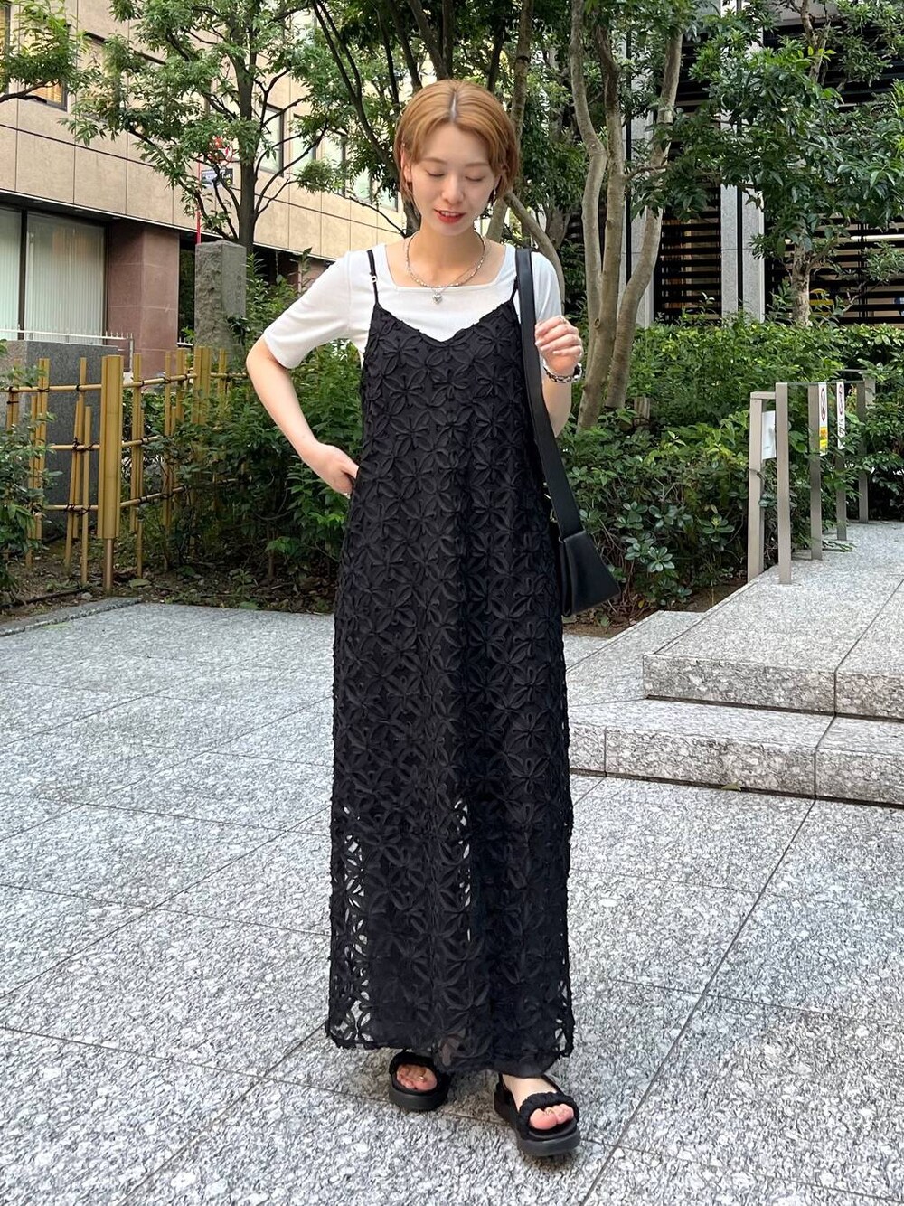 ブラック系のサンダル、ブラック系のショルダーバッグ、ホワイト系のTシャツ/カットソーを着用したレディースの夏コーディネートの1枚目の写真