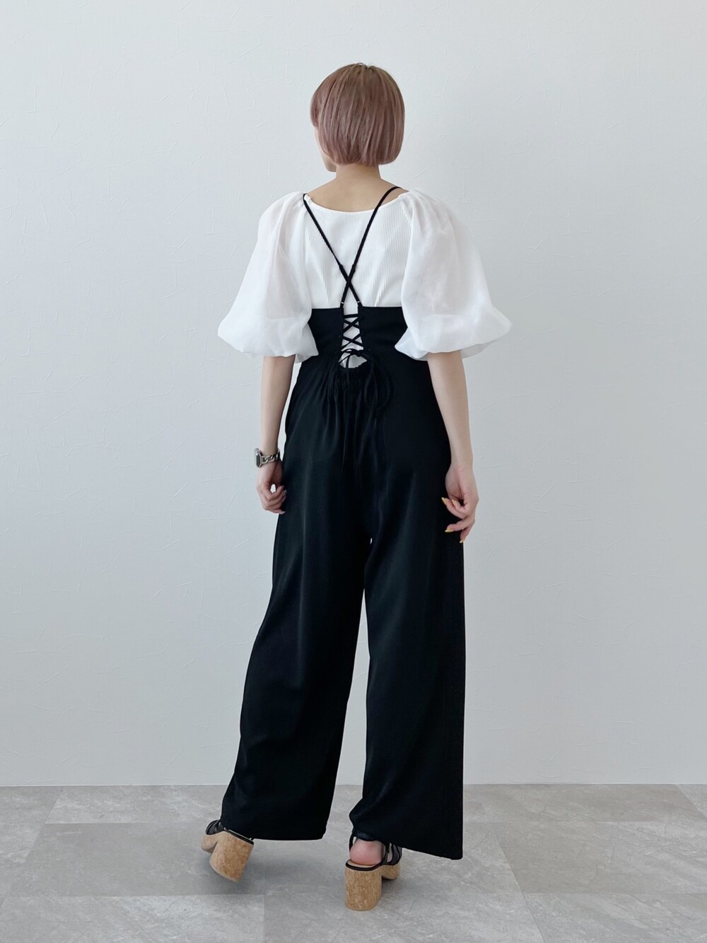 ホワイト系のシャツ/ブラウス、ブラック系のサロペット/オーバーオール、ブラック系のサンダルを着用したレディースの春コーディネートの2枚目の写真