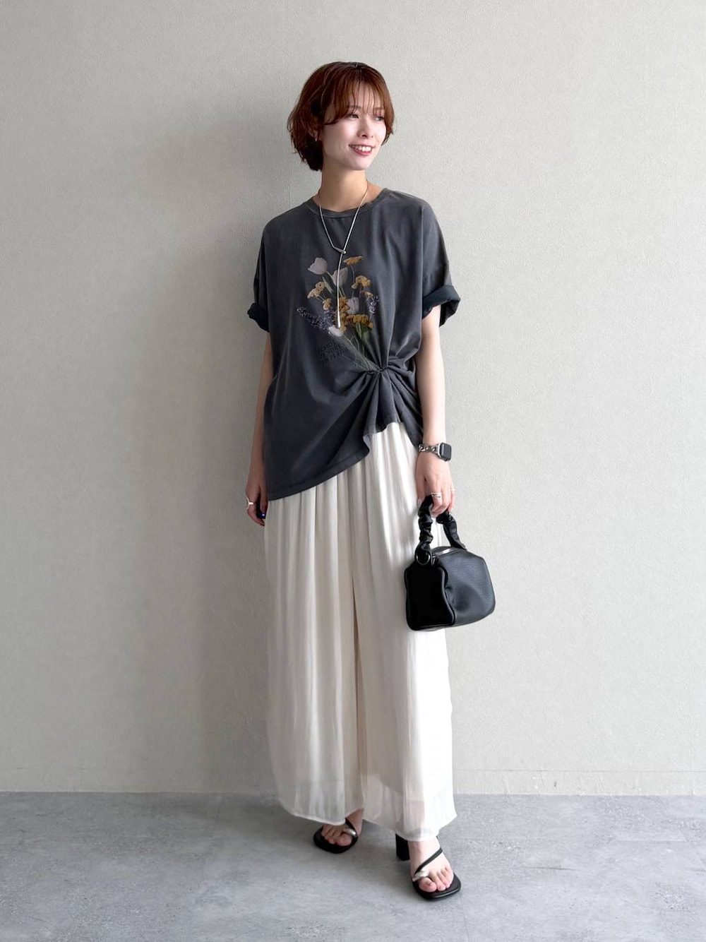 ブラック系のショルダーバッグ、グレー系のTシャツ/カットソー、ブラック系のサンダルを着用したレディースの夏コーディネートの1枚目の写真