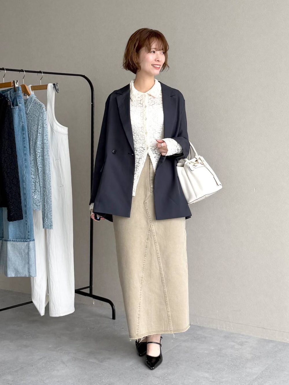 ブラック系のサンダル、ブルー系のテーラードジャケット、ベージュ系のスカートを着用したレディースの春コーディネートの1枚目の写真