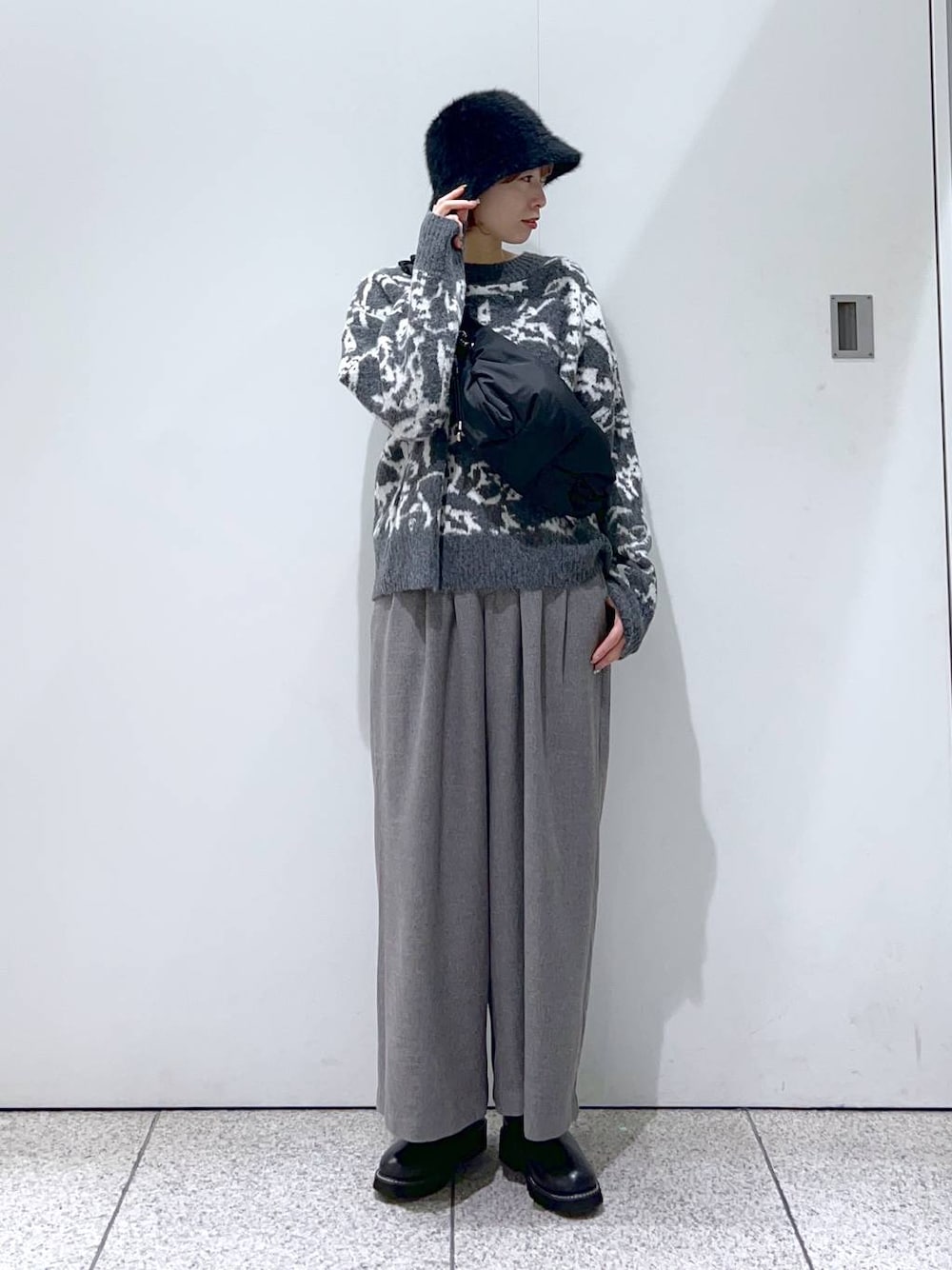 ブラック系のハンドバッグ、ブラック系のブーツ、グレー系のニット/セーターを着用したレディースの冬コーディネートの1枚目の写真