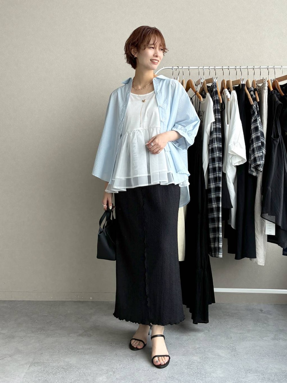 ブラック系のスカート、グレー系のニット/セーター、ブルー系のシャツ/ブラウスを着用したレディースの夏コーディネートの1枚目の写真