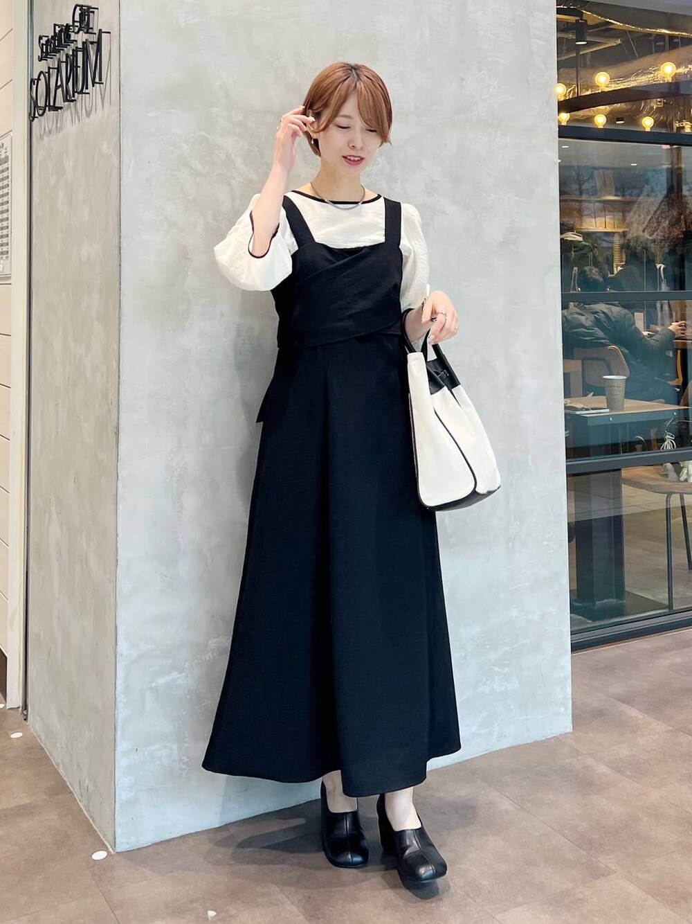 ブラック系のトートバッグ、ホワイト系のシャツ/ブラウス、ブラック系のパンプスを着用したレディースの春コーディネートの1枚目の写真