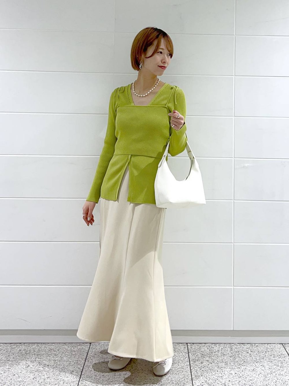 ベージュ系のスカート、シルバー系のバレエシューズ、グリーン系のカーディガン/ボレロを着用したレディースの春コーディネートの1枚目の写真