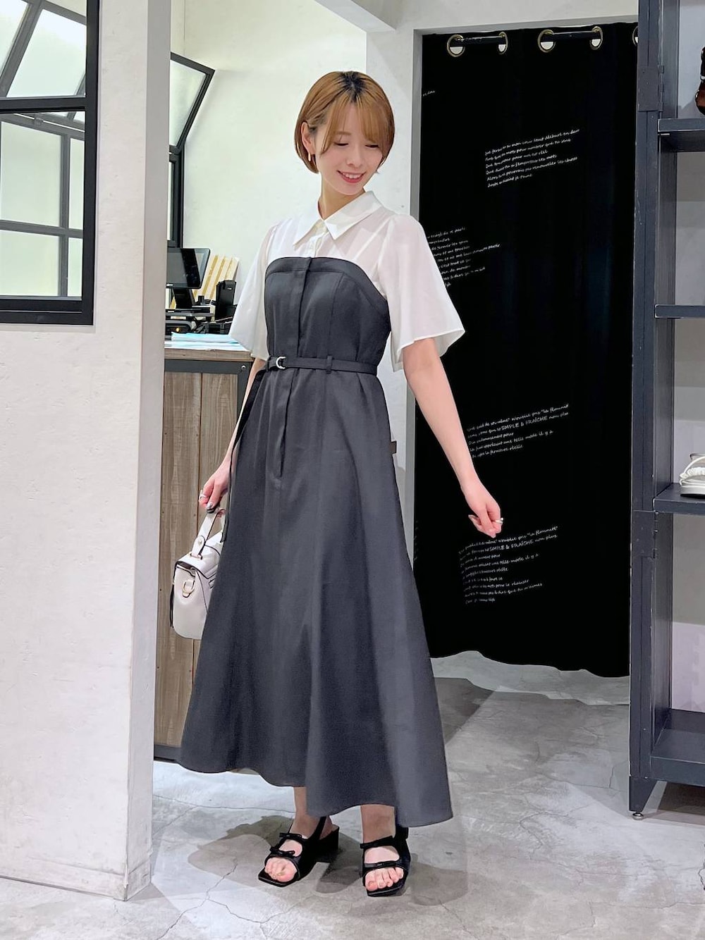 ブラック系のサンダル、グレー系のワンピース、ホワイト系のショルダーバッグを着用したレディースの春コーディネートの1枚目の写真