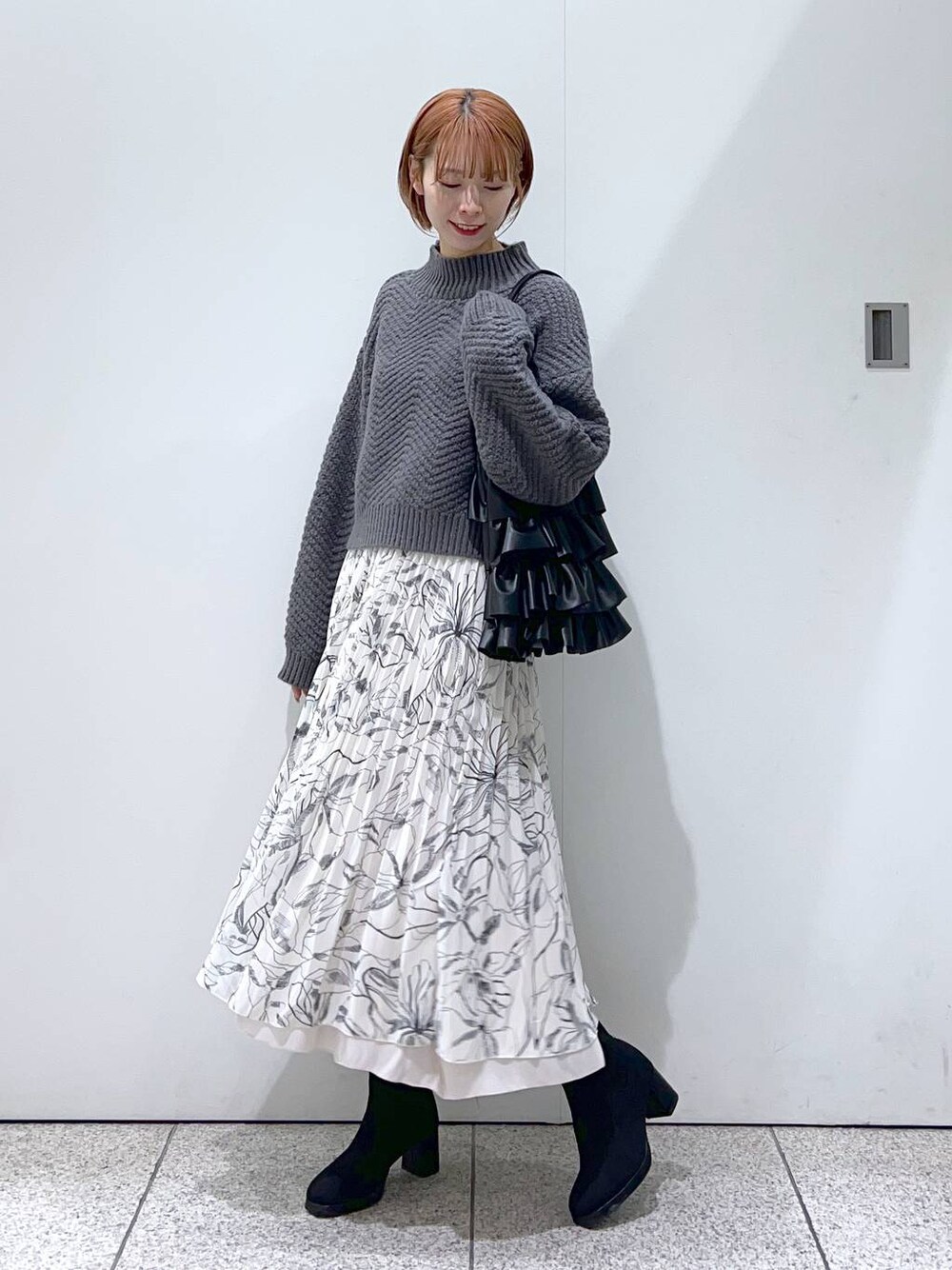 ブラック系のブーツ、ホワイト系のスカート、ブラック系のトートバッグを着用したレディースの冬コーディネートの1枚目の写真