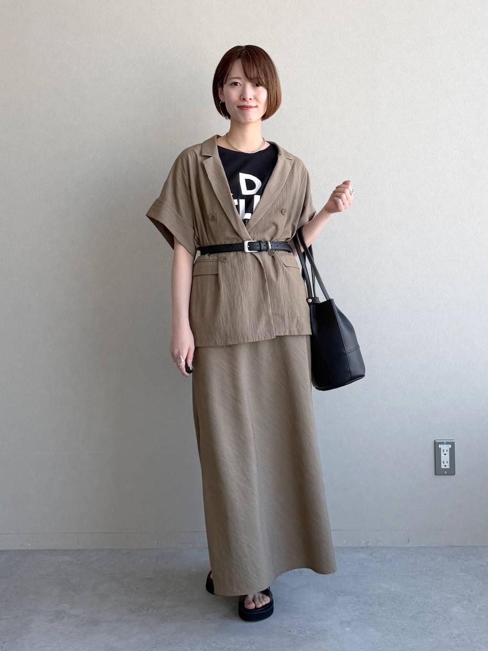ブラック系のサンダル、ブラック系のTシャツ/カットソー、ブラウン系のスカートを着用したレディースの春コーディネートの1枚目の写真