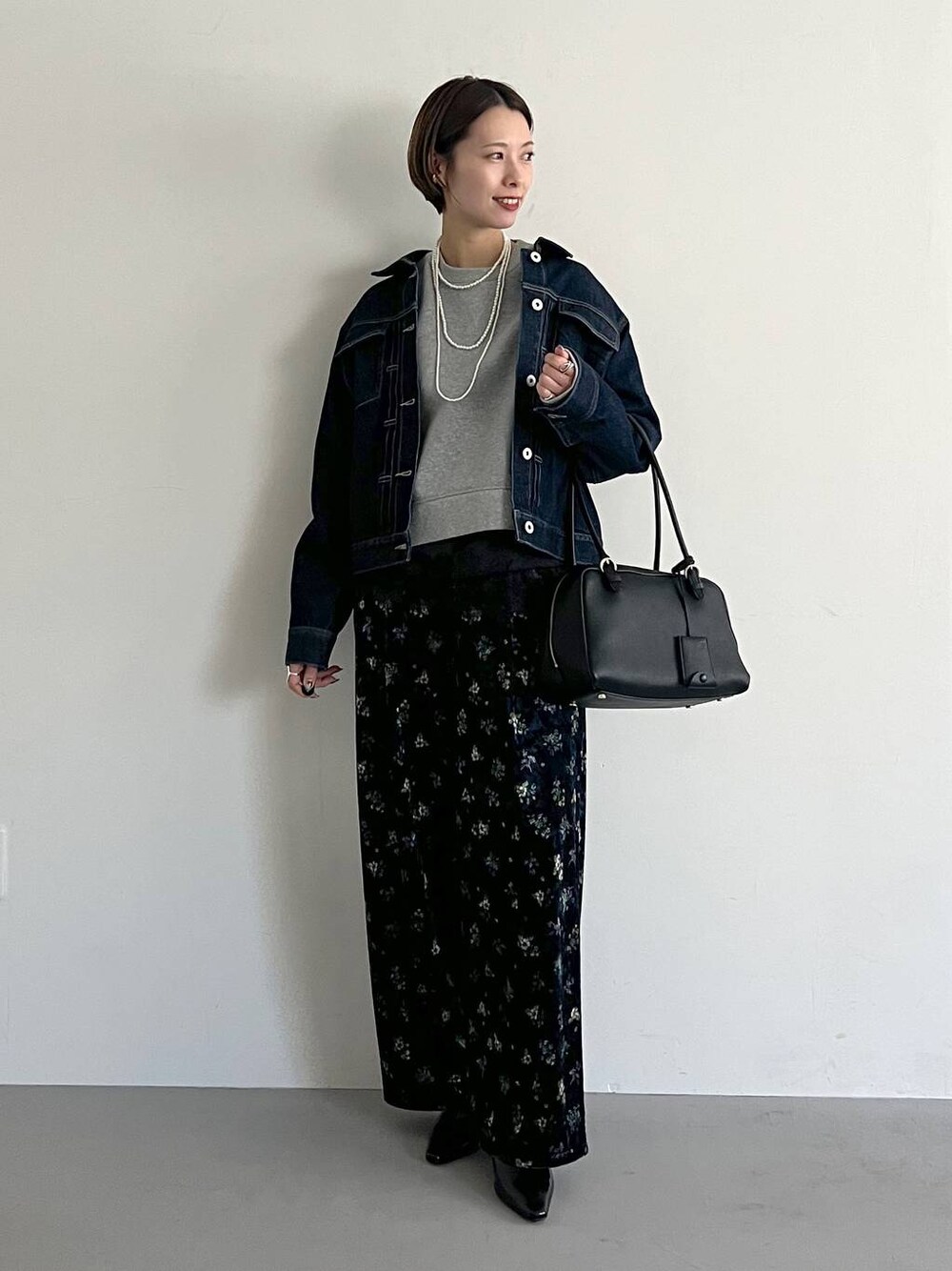 ブラック系のハンドバッグ、グレー系のスウェット、ブルー系のデニムジャケットを着用したレディースの冬コーディネートの1枚目の写真
