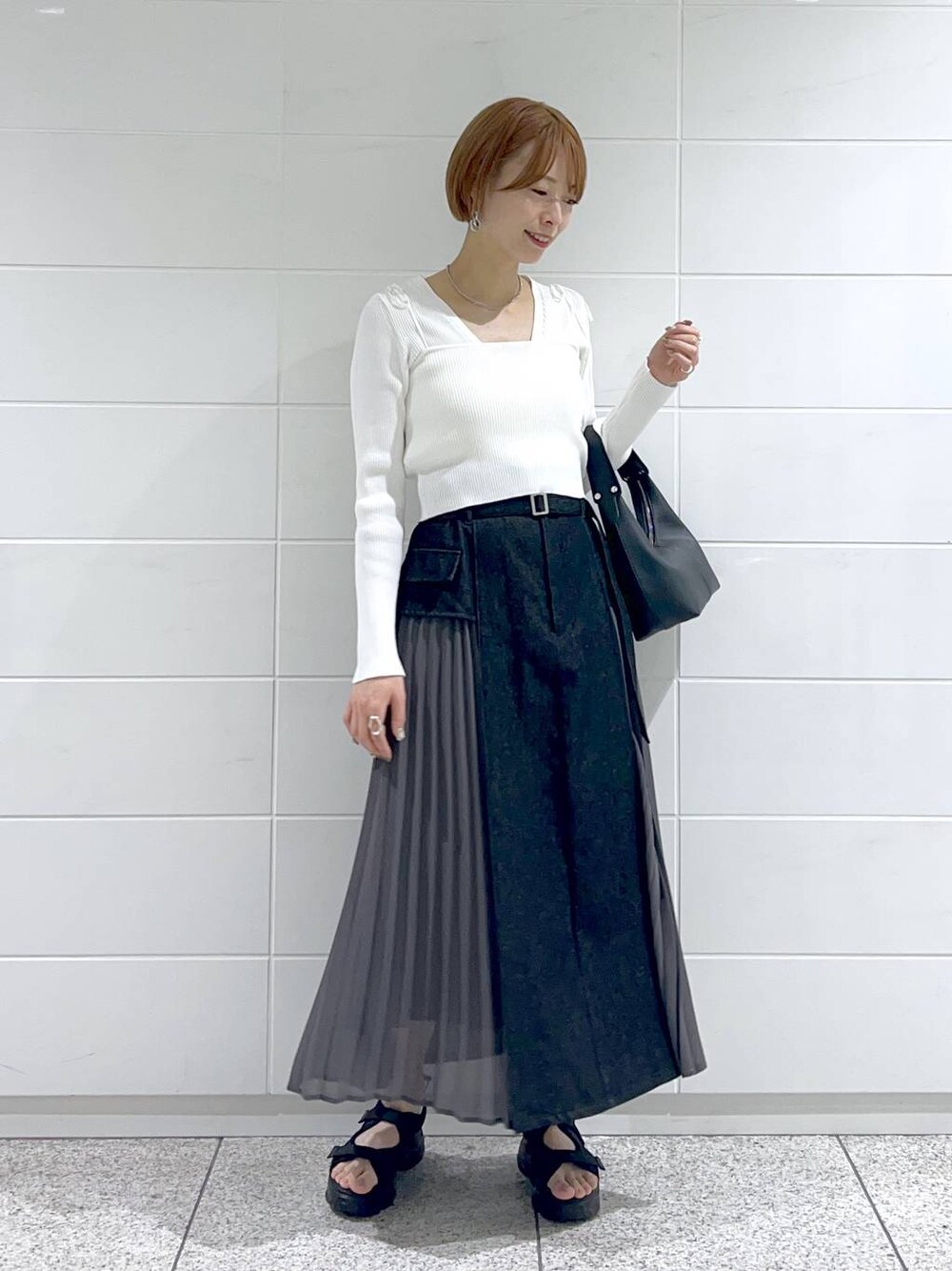 ブラック系のスカート、ホワイト系のカーディガン/ボレロ、ブラック系のサンダルを着用したレディースの春コーディネートの1枚目の写真