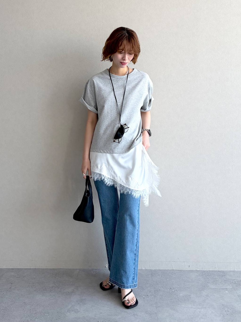 ブルー系のデニムパンツ、グレー系のTシャツ/カットソー、ブラック系のショルダーバッグを着用したレディースの春コーディネートの1枚目の写真
