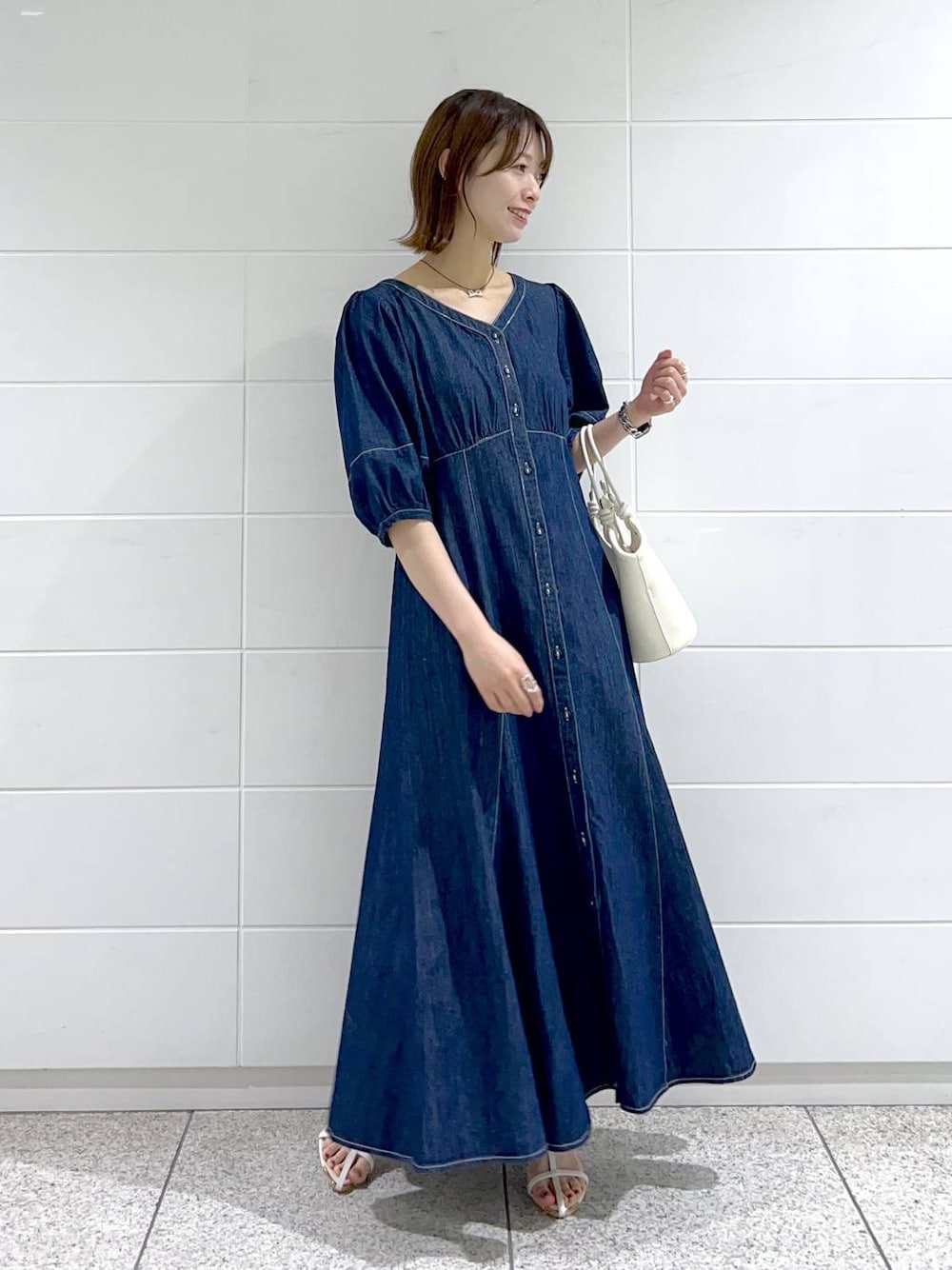 ブルー系のワンピース、ホワイト系のサンダル、ホワイト系のハンドバッグを着用したレディースの春コーディネートの1枚目の写真