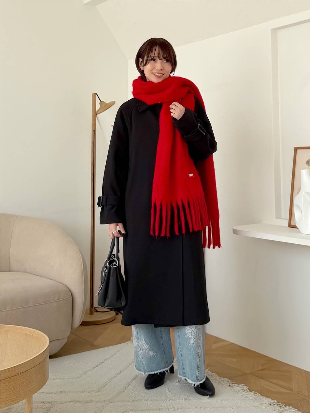 ブルー系のデニムパンツ、ブラック系のショルダーバッグ、ブラック系のチェスターコートを着用したレディースの秋コーディネートの1枚目の写真