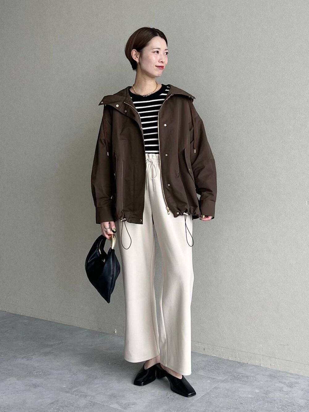 ブラック系のハンドバッグ、ブラウン系のマウンテンパーカー、ブラック系のスリッポンを着用したレディースの秋コーディネートの1枚目の写真