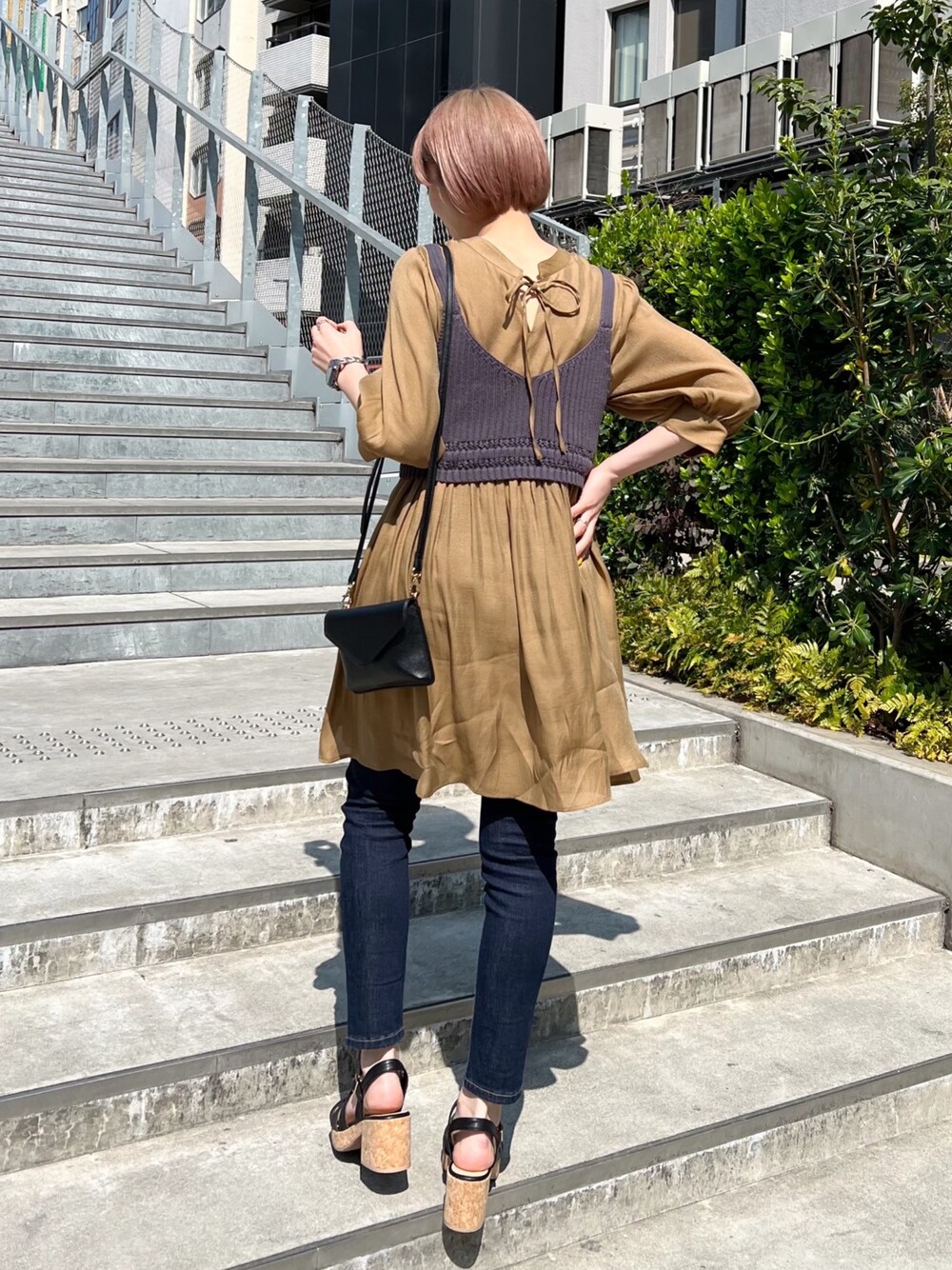 ブルー系のデニムパンツ、ブラック系のサンダル、グレー系のワンピースを着用したレディースの春コーディネートの2枚目の写真