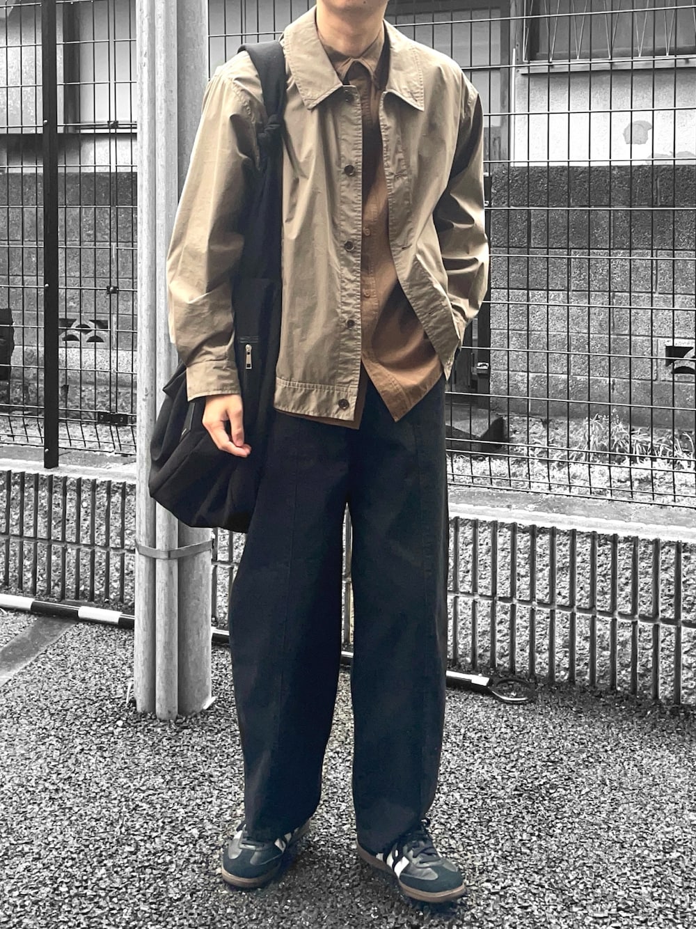 ブラック系のスニーカー、ブラック系のデニムパンツ、ブラック系のショルダーバッグを着用したメンズの冬コーディネートの1枚目の写真