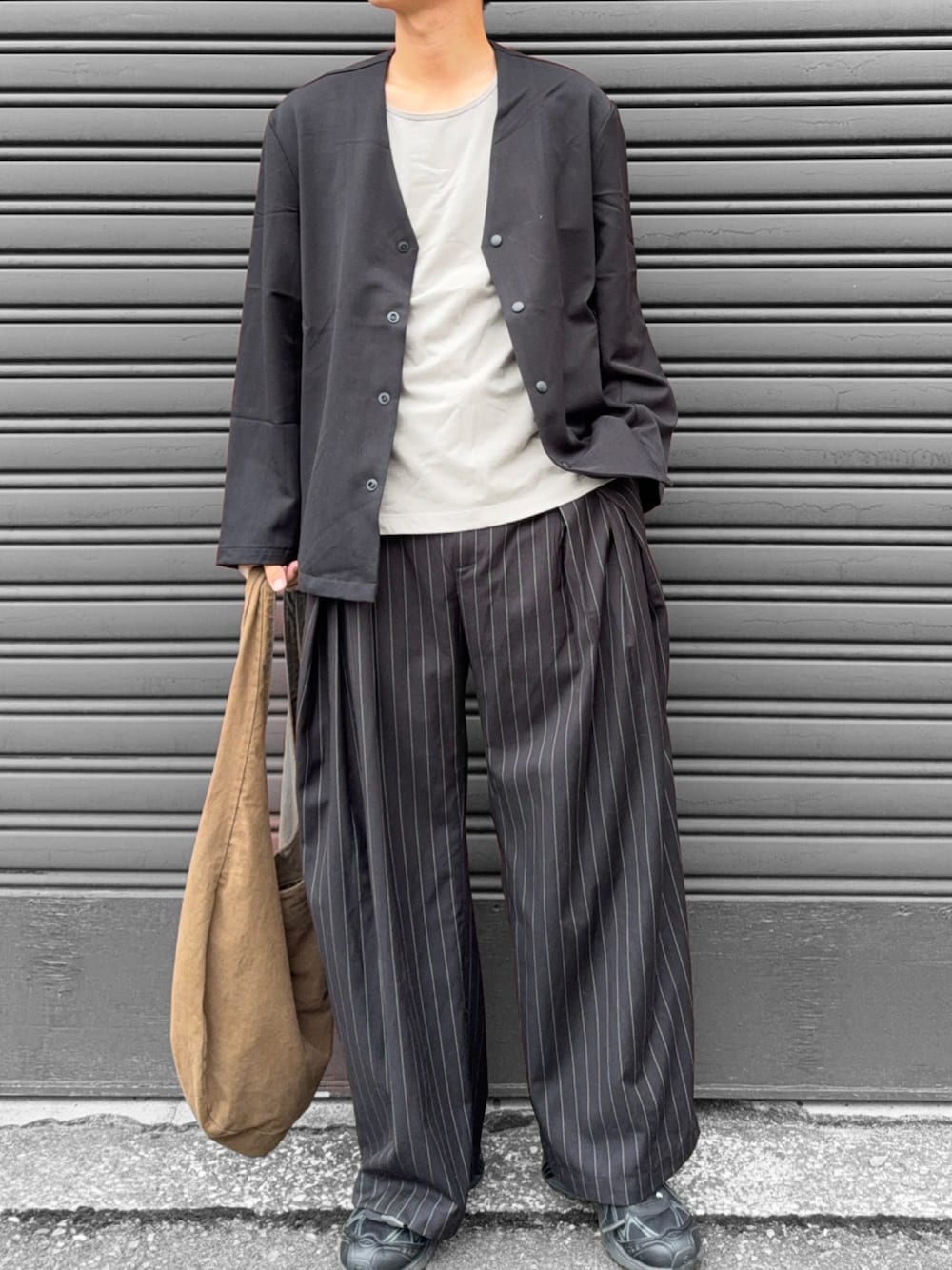 グレー系のタンクトップ、ブラック系のカーディガン/ボレロ、ブラック系のスラックスを着用したメンズの秋コーディネートの1枚目の写真