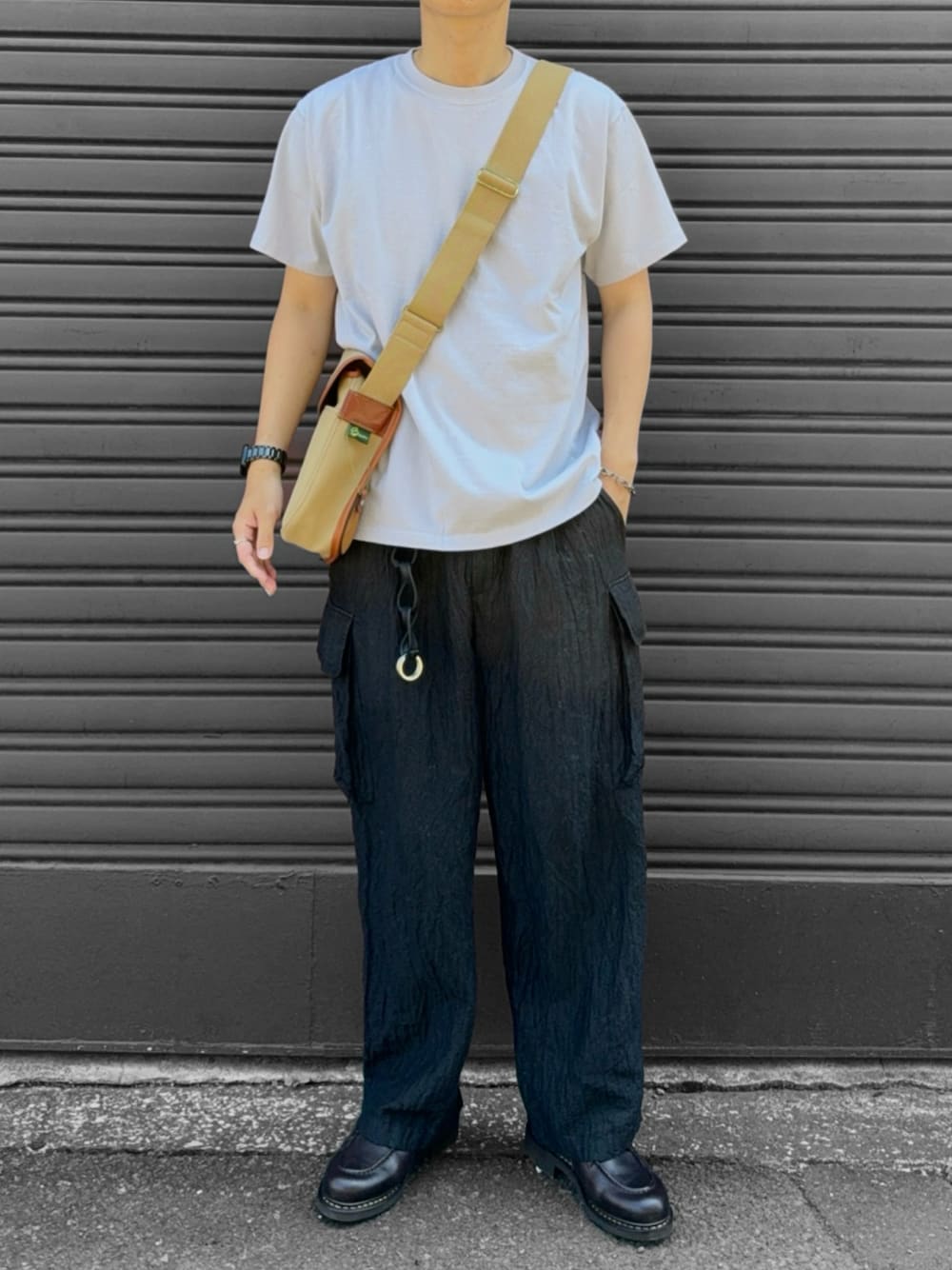 ベージュ系のショルダーバッグ、ブラウン系のモカシン/デッキシューズ、ベージュ系のTシャツ/カットソーを着用したメンズの秋コーディネートの1枚目の写真