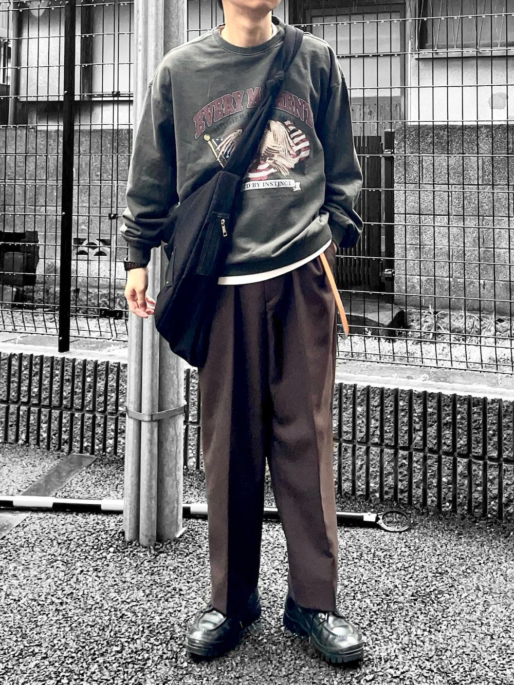 ブラック系のスウェット、ブラック系のショルダーバッグ、ブラウン系のスラックスを着用したメンズの春コーディネートの1枚目の写真