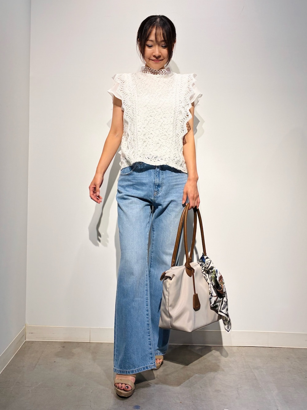 グレー系のデニムパンツ、ベージュ系のトートバッグ、ホワイト系のトップスを着用したレディースの夏コーディネートの1枚目の写真