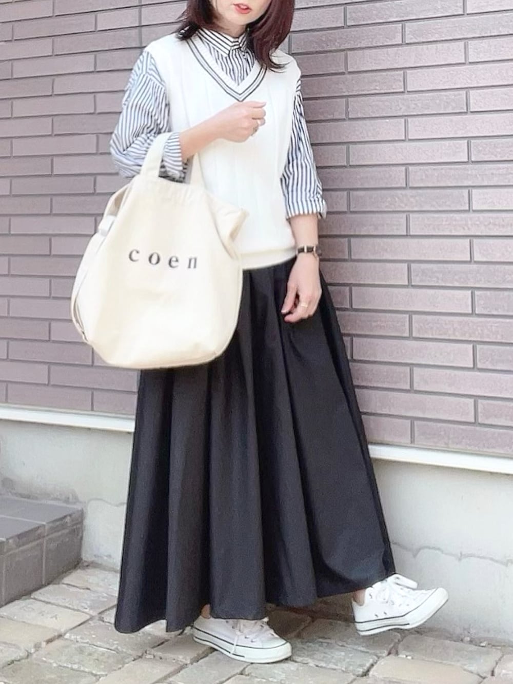 ホワイト系のベスト、ブルー系のシャツ/ブラウス、ブラック系のスカートを着用したレディースの春コーディネートの1枚目の写真