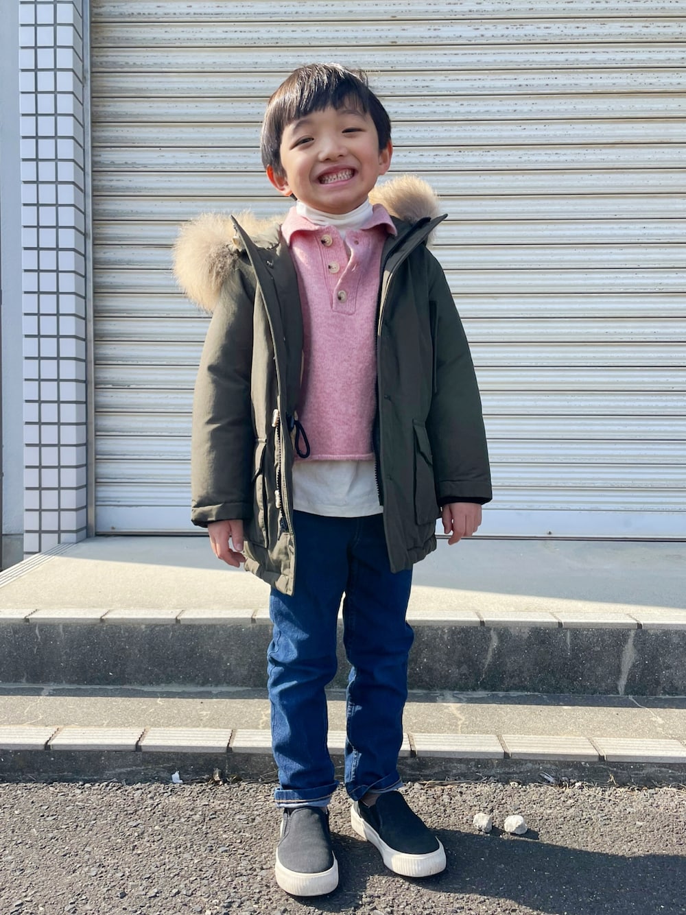 ブルー系のデニムパンツ、ブラック系のスリッポン、ピンク系のニット/セーターを着用したキッズの冬コーディネートの1枚目の写真