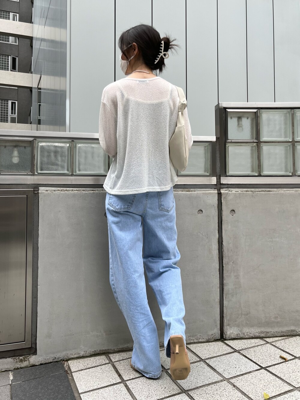 ブルー系のデニムパンツ、ベージュ系のカーディガン/ボレロ、グリーン系のキャミソールを着用したレディースの夏コーディネートの2枚目の写真