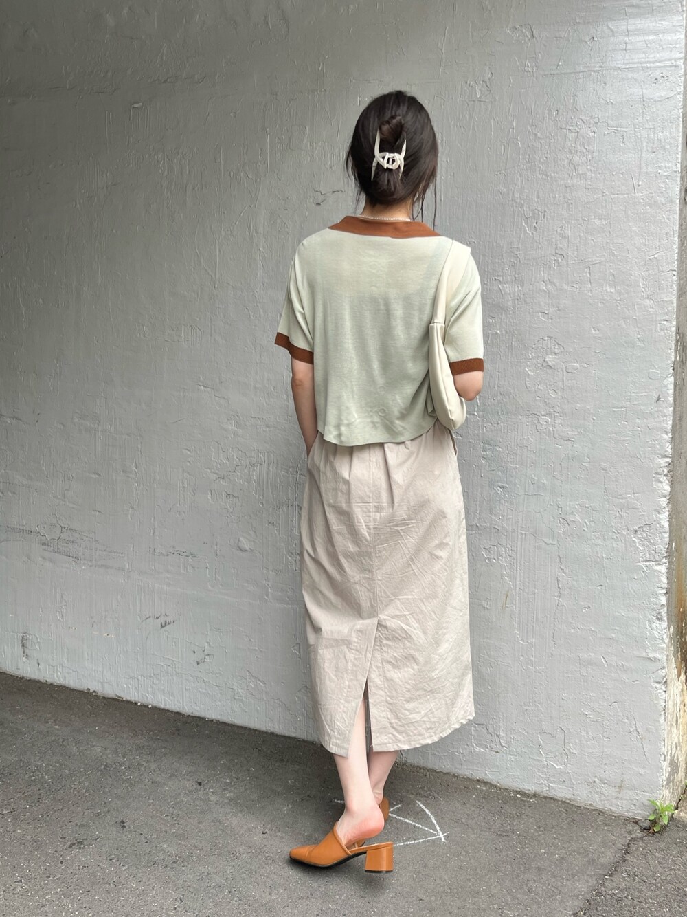 グリーン系のポロシャツ、ベージュ系のスカート、ブラウン系のシューズを着用したレディースの夏コーディネートの2枚目の写真