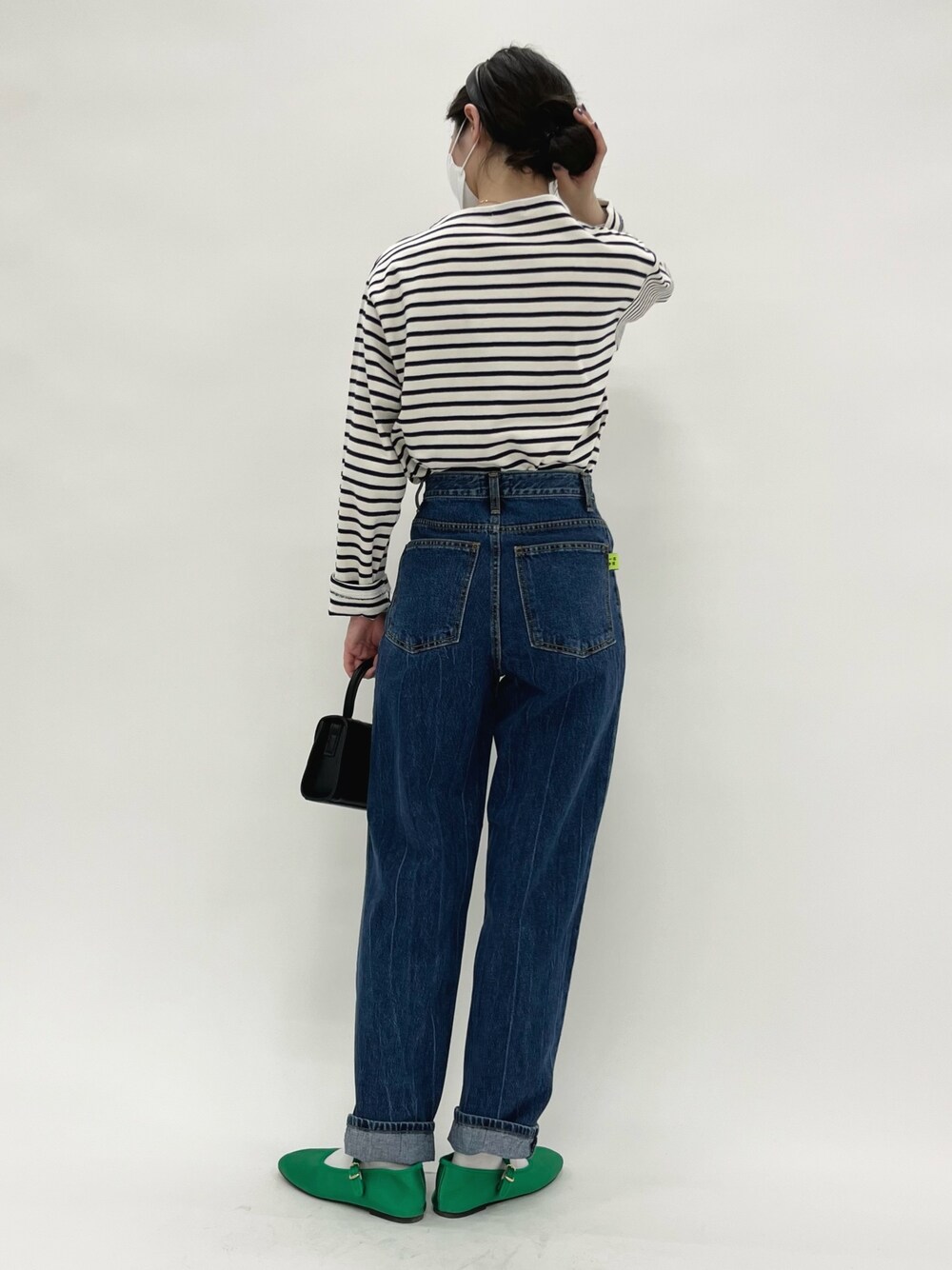 ベージュ系のTシャツ/カットソー、ブルー系のデニムパンツ、グリーン系のパンプスを着用したレディースの冬コーディネートの3枚目の写真