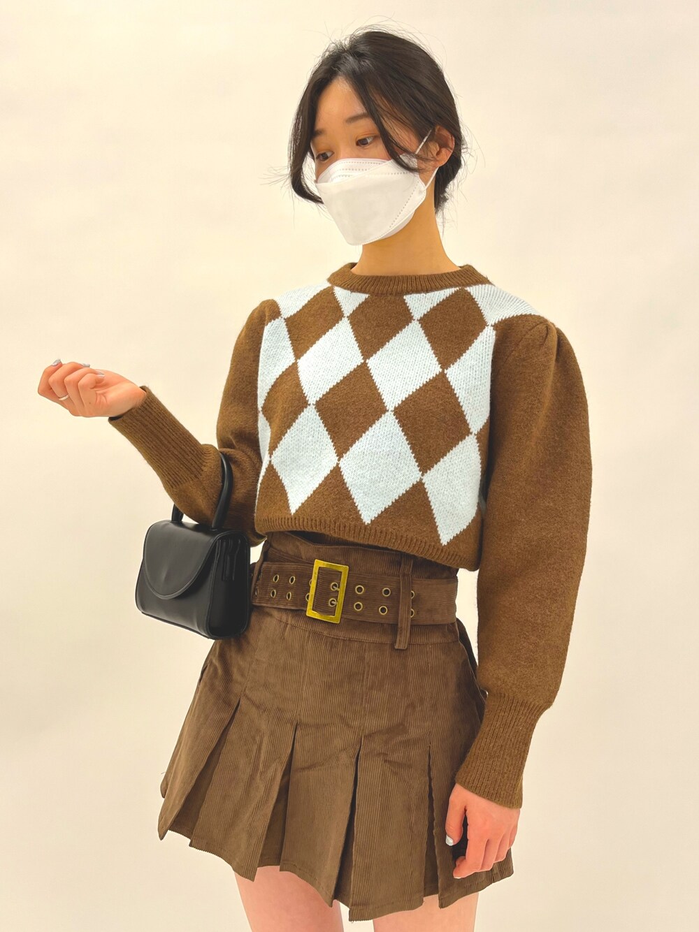 ブラウン系のスカート、ブラウン系のニット/セーター、ブラック系のショルダーバッグを着用したレディースの冬コーディネートの4枚目の写真