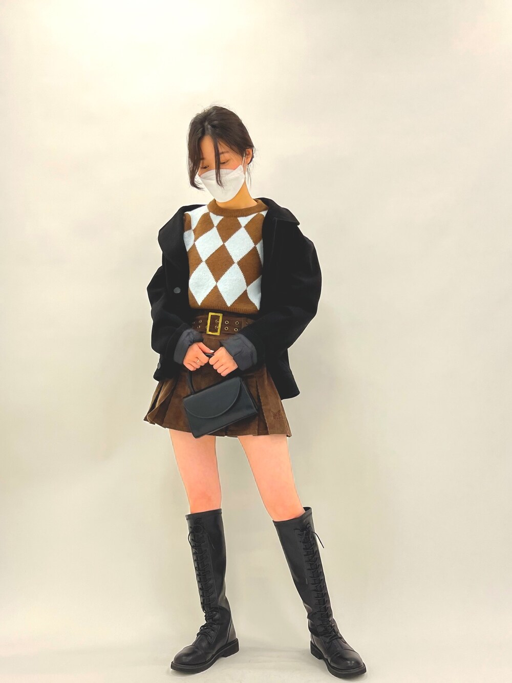 ブラウン系のスカート、ブラウン系のニット/セーター、ブラック系のショルダーバッグを着用したレディースの冬コーディネートの2枚目の写真