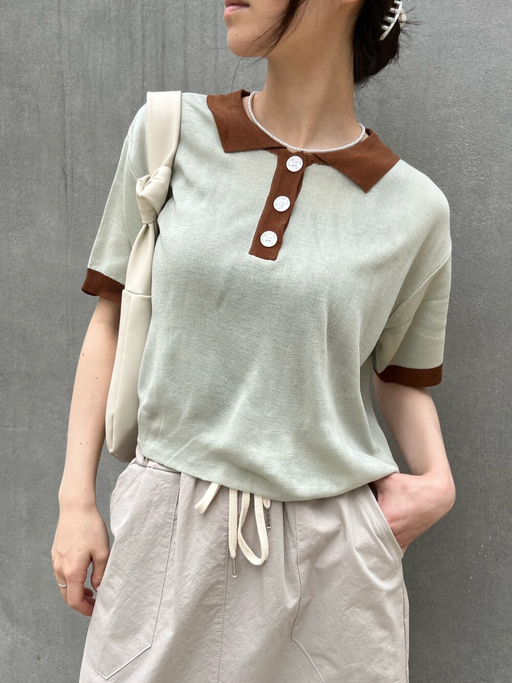 グリーン系のポロシャツ、ベージュ系のスカート、ブラウン系のシューズを着用したレディースの夏コーディネートの3枚目の写真