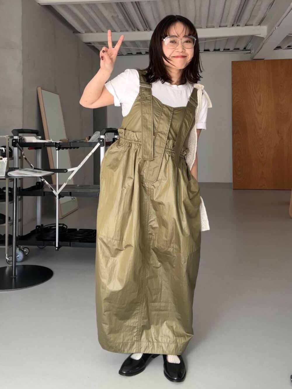 ブラック系のローファー、ホワイト系のショルダーバッグ、グリーン系のワンピースを着用したレディースの冬コーディネートの1枚目の写真