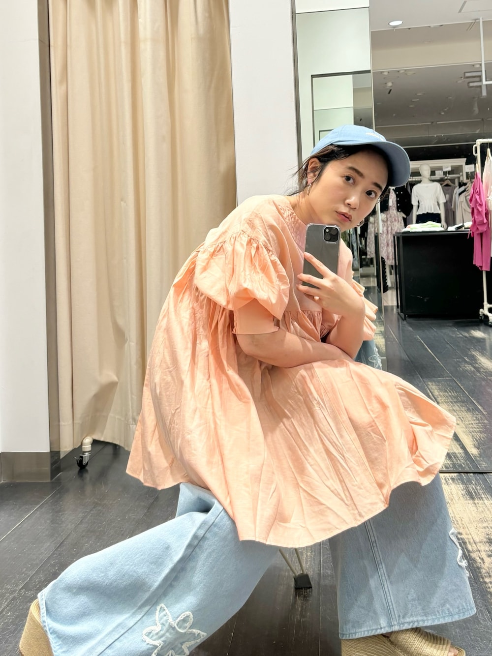 オレンジ系のワンピース、ブルー系のデニムパンツを着用したレディースの春コーディネートの1枚目の写真