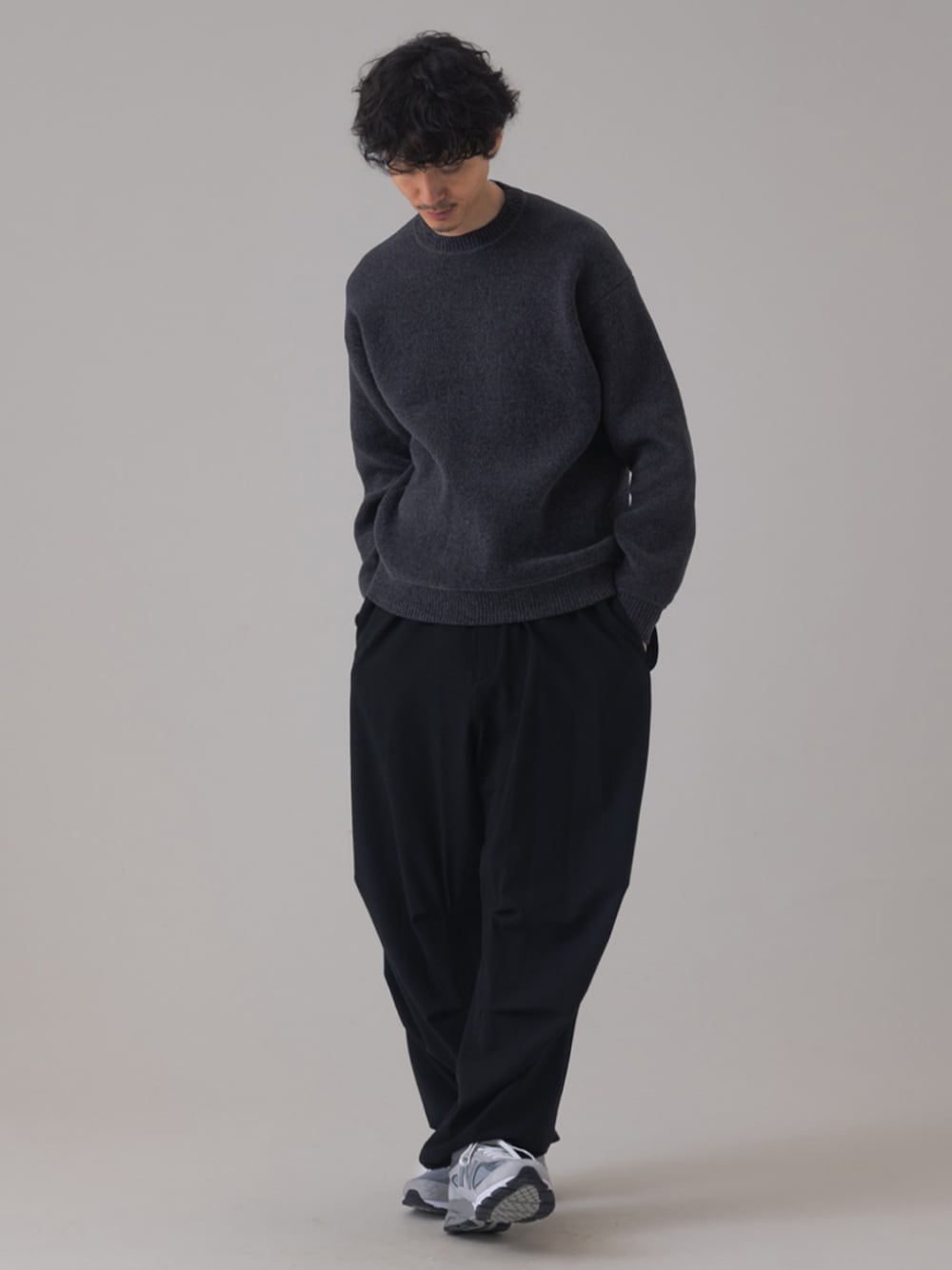 グレー系のスニーカー、ブラック系のスラックス、グレー系のニット/セーターを着用したメンズの秋コーディネートの1枚目の写真