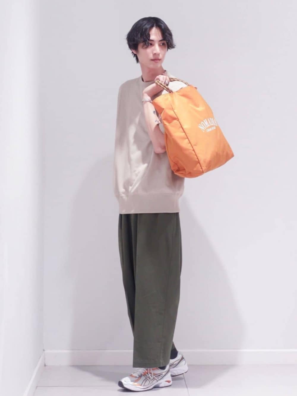 ブラウン系のトートバッグ、ホワイト系のスニーカー、ベージュ系のTシャツ/カットソーを着用したメンズの春コーディネートの1枚目の写真