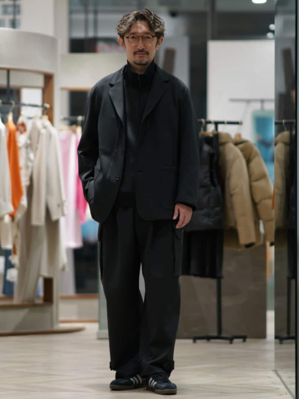 ブラック系のカーゴパンツ、ブラック系のテーラードジャケット、ブラック系のスニーカーを着用したメンズの冬コーディネートの1枚目の写真