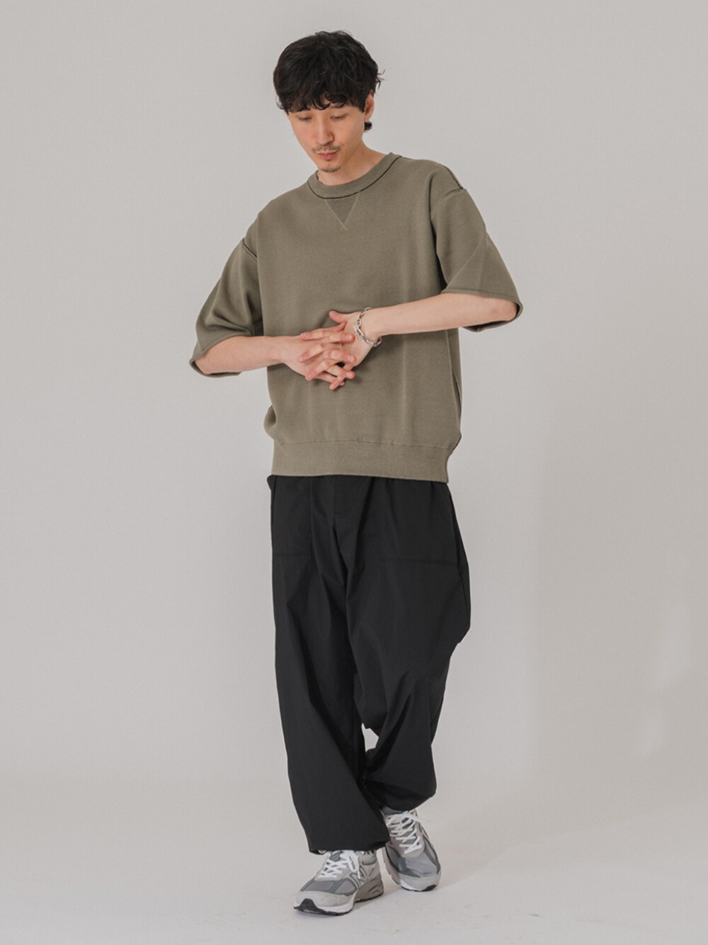 グレー系のスニーカー、ブラック系のその他パンツ、グリーン系のニット/セーターを着用したメンズの春コーディネートの1枚目の写真