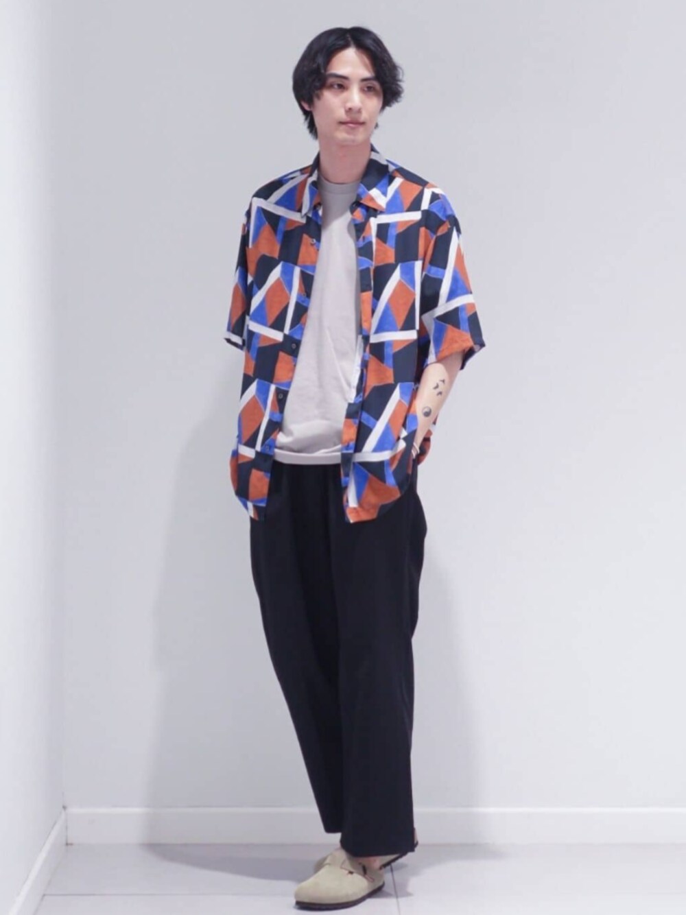 ブラック系のスラックス、ブルー系のシャツ/ブラウス、ベージュ系のTシャツ/カットソーを着用したメンズの夏コーディネートの1枚目の写真