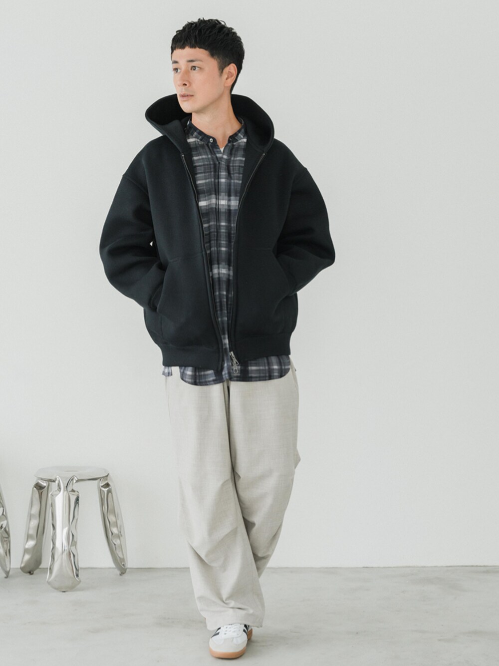 ホワイト系のスニーカー、ホワイト系のスラックス、ブラック系のパーカーを着用したメンズの秋コーディネートの1枚目の写真