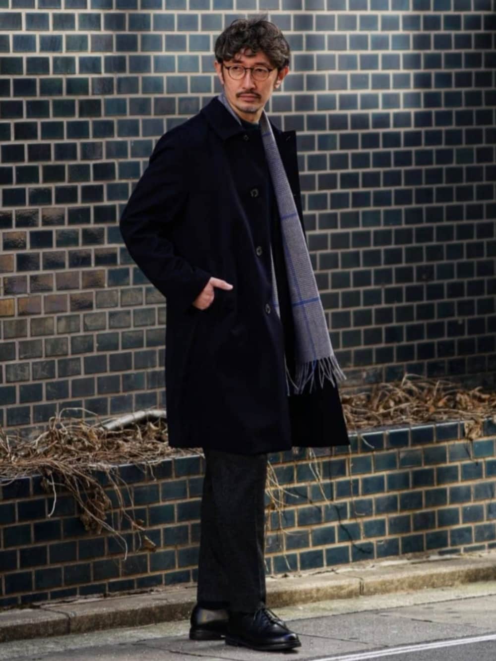 ブルー系のチェスターコート、ブラック系のスラックス、グレー系のマフラーを着用したメンズの冬コーディネートの1枚目の写真