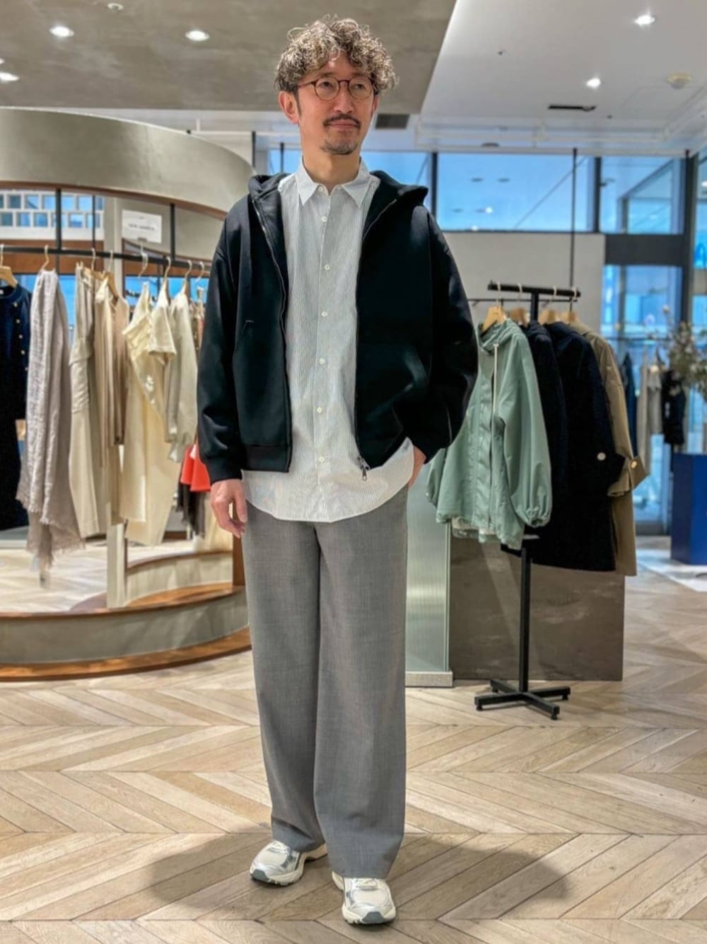 ブルー系のシャツ/ブラウス、ブラック系のパーカー、グレー系のスラックスを着用したメンズの春コーディネートの1枚目の写真