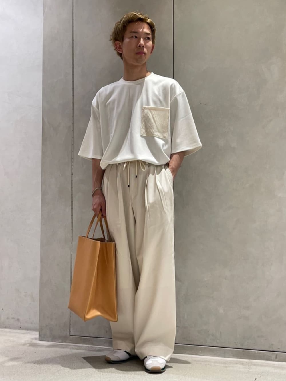 ホワイト系のスラックス、ホワイト系のTシャツ/カットソー、ベージュ系のトートバッグを着用したメンズの夏コーディネートの1枚目の写真